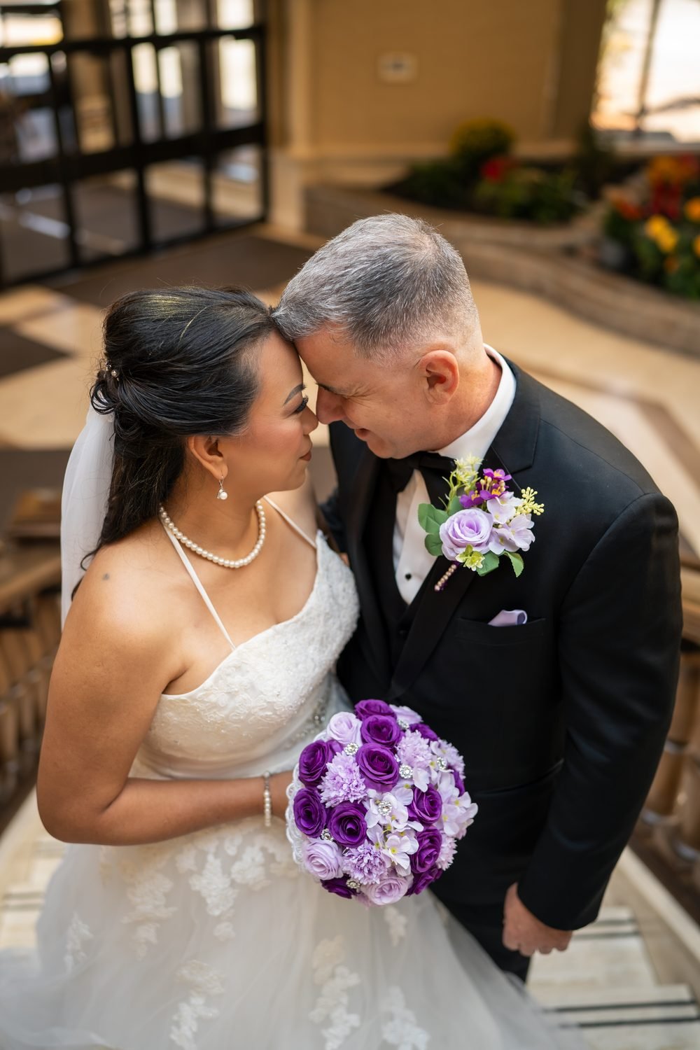 Bride and groom forehead to forehead with a purple bouquet at a Caboto Club wedding in Windsor, Ontario