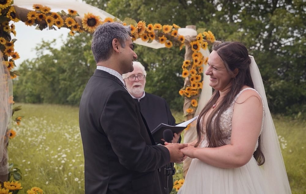 Bride and groom exchanging vows beneath a sunflower arch at a wedding near Windsor