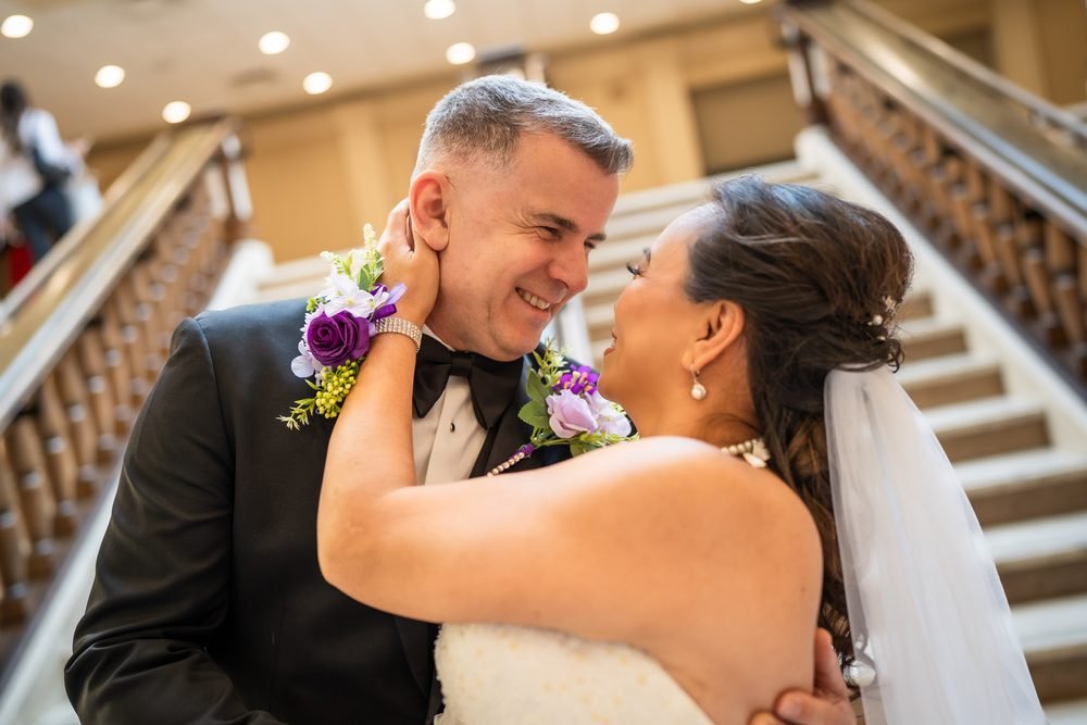 Bride and groom embracing on a grand staircase at the Giovanni Caboto Club in Windsor