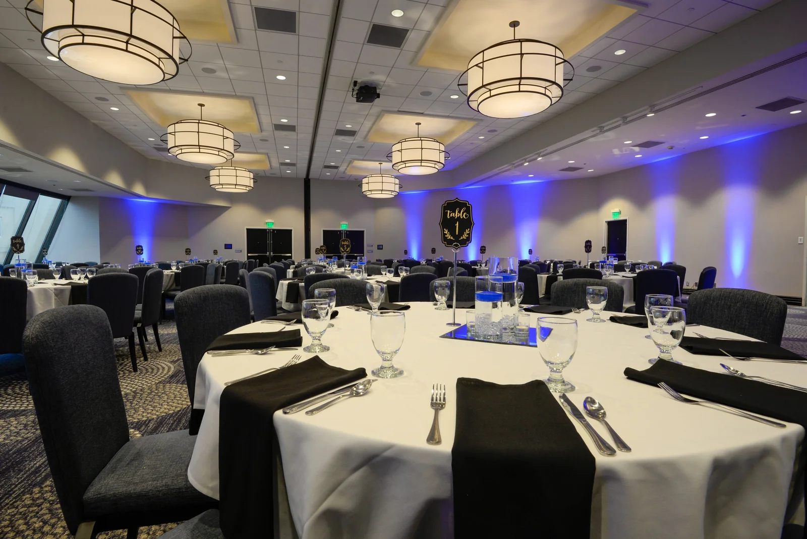 Elegant ballroom event setup in Windsor Ontario with round tables and blue uplighting for a corporate event